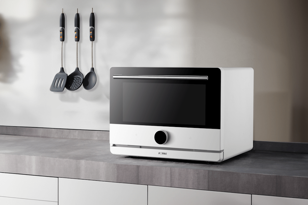 White countertop convection oven with glass door and control knob on a gray kitchen counter