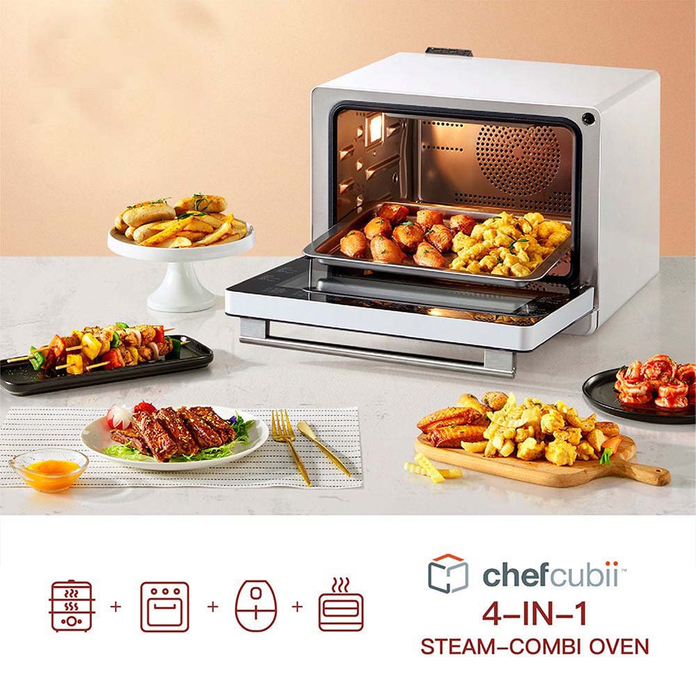 A FOTILE Combi Steam Oven with dishes of food surrounding it. The oven door is open, revealing cooked drumsticks inside. Various dishes, including fries, vegetables, and seafood, are arranged around the oven. The text "FOTILE Combi Steam Oven" is shown prominently.